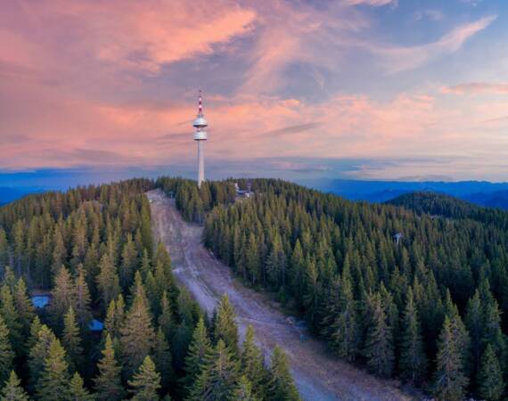 Snezhanka tower in valley of Rhodope mountains and forests against clouds. Panorama, top view